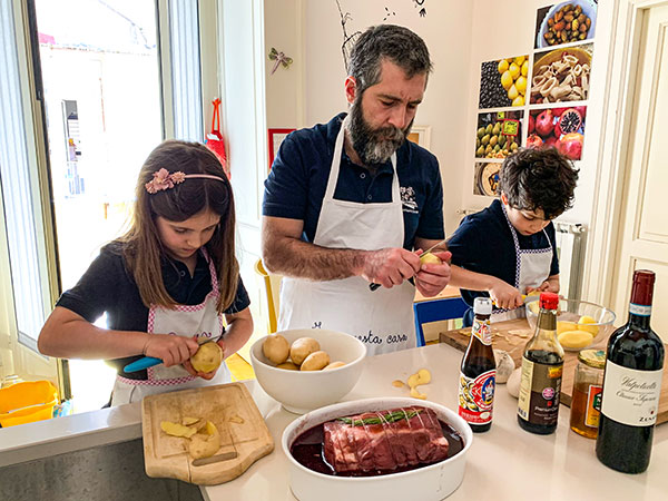 famiglia in cucina papà e bambini cucinano arista maiale