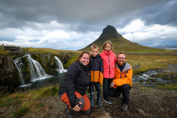 famiglia in Islanda davanti a una cascata con un monte sullo sfondo. Itinerario in Islanda low cost
